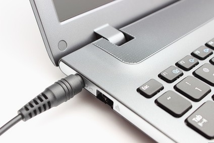 Picture of a laptop with charging cord plugged in.
